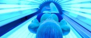 young woman at laying on solarium bed and get brown skin tone ready for summer