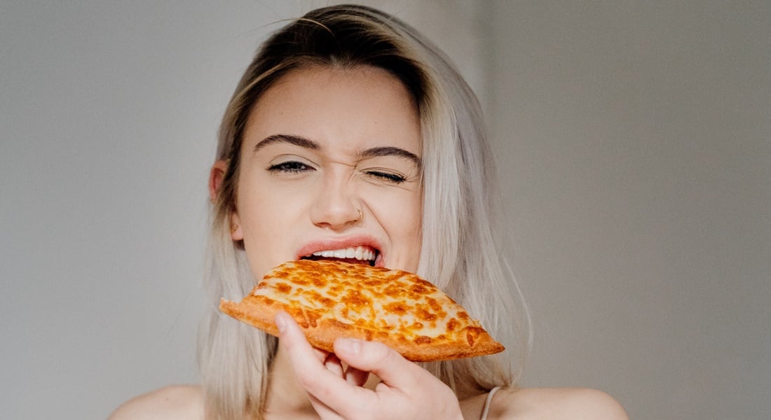 Mladá žena s kúskom pizze v ruke