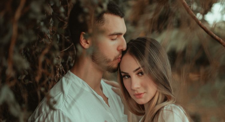 Muž bozkáva ženu na hlavu