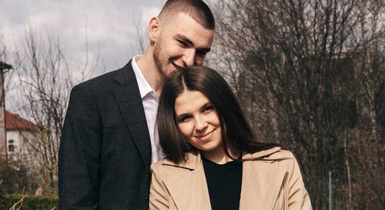 Muž stojí za ženou a usmievajú sa
