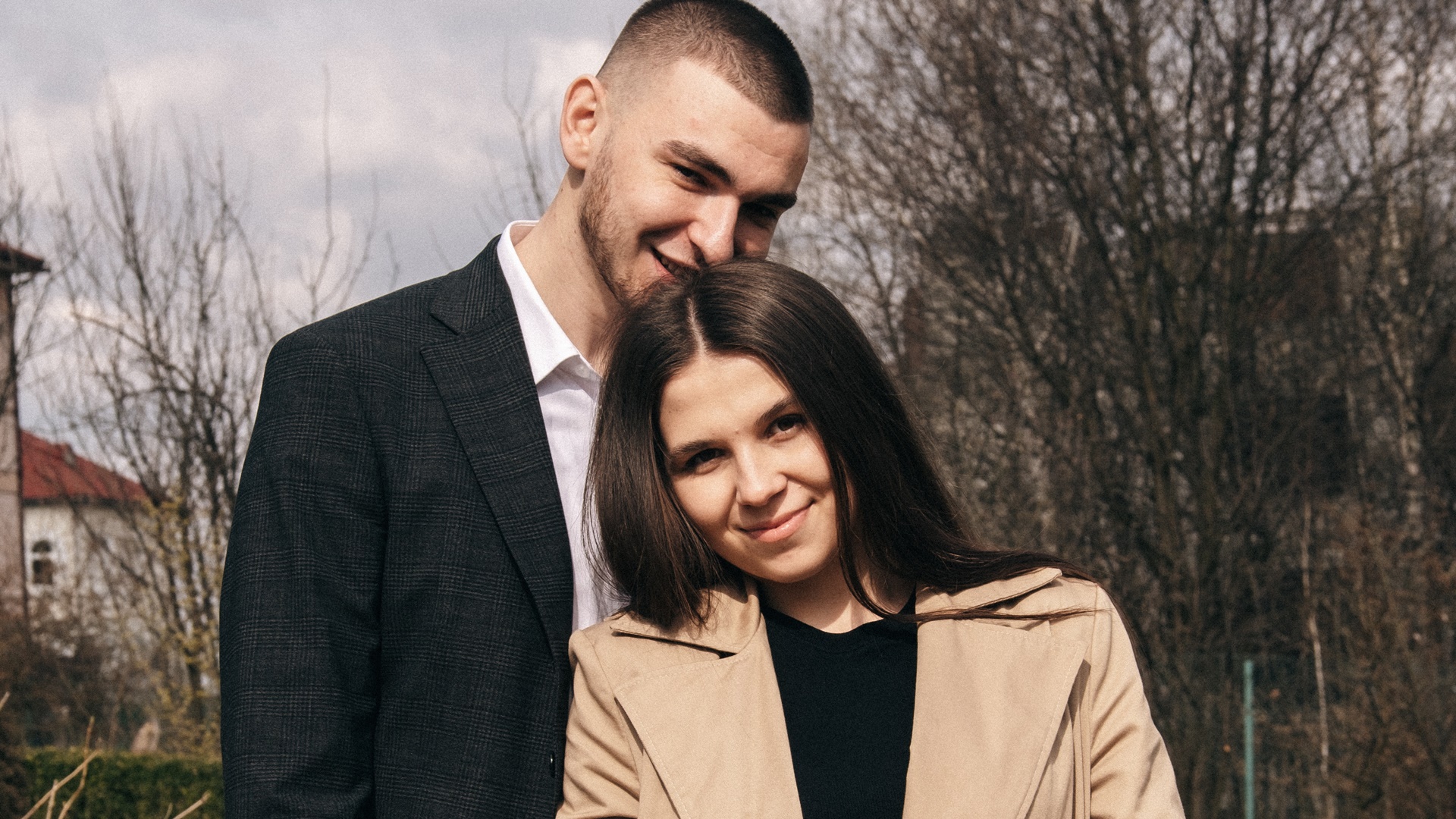 Muž stojí za ženou a usmievajú sa