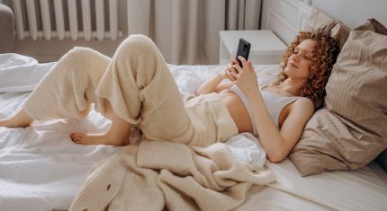 Žena leží v posteli a hrá sa na mobile