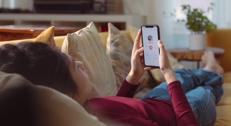 Žena leží na gauči s mobilom v ruke