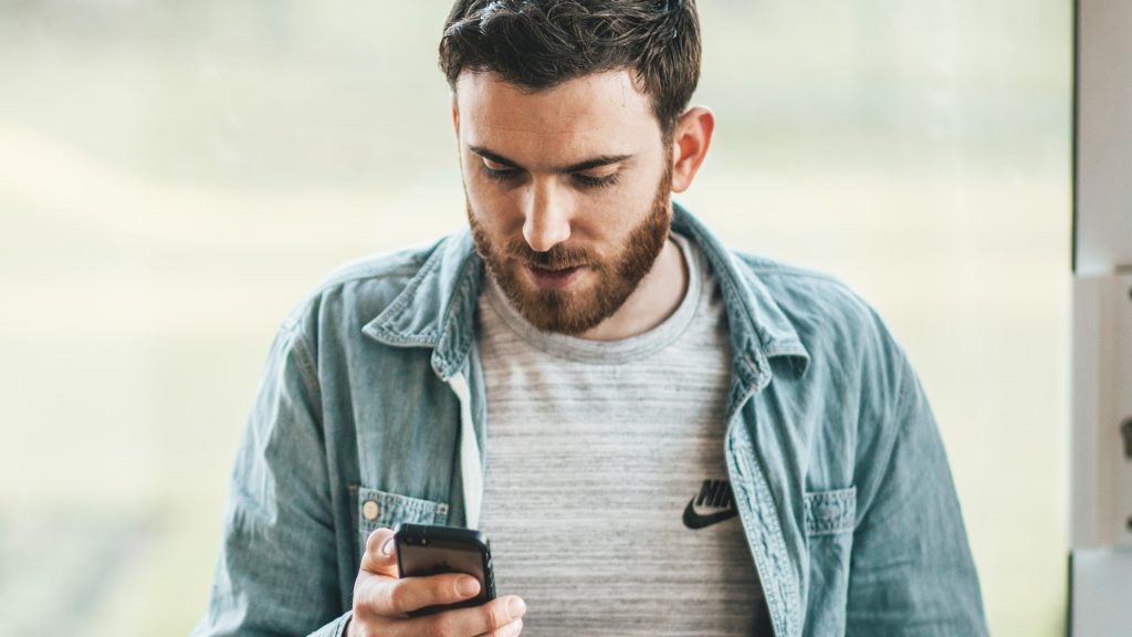 Muž po rozchode pozerá do mobilu