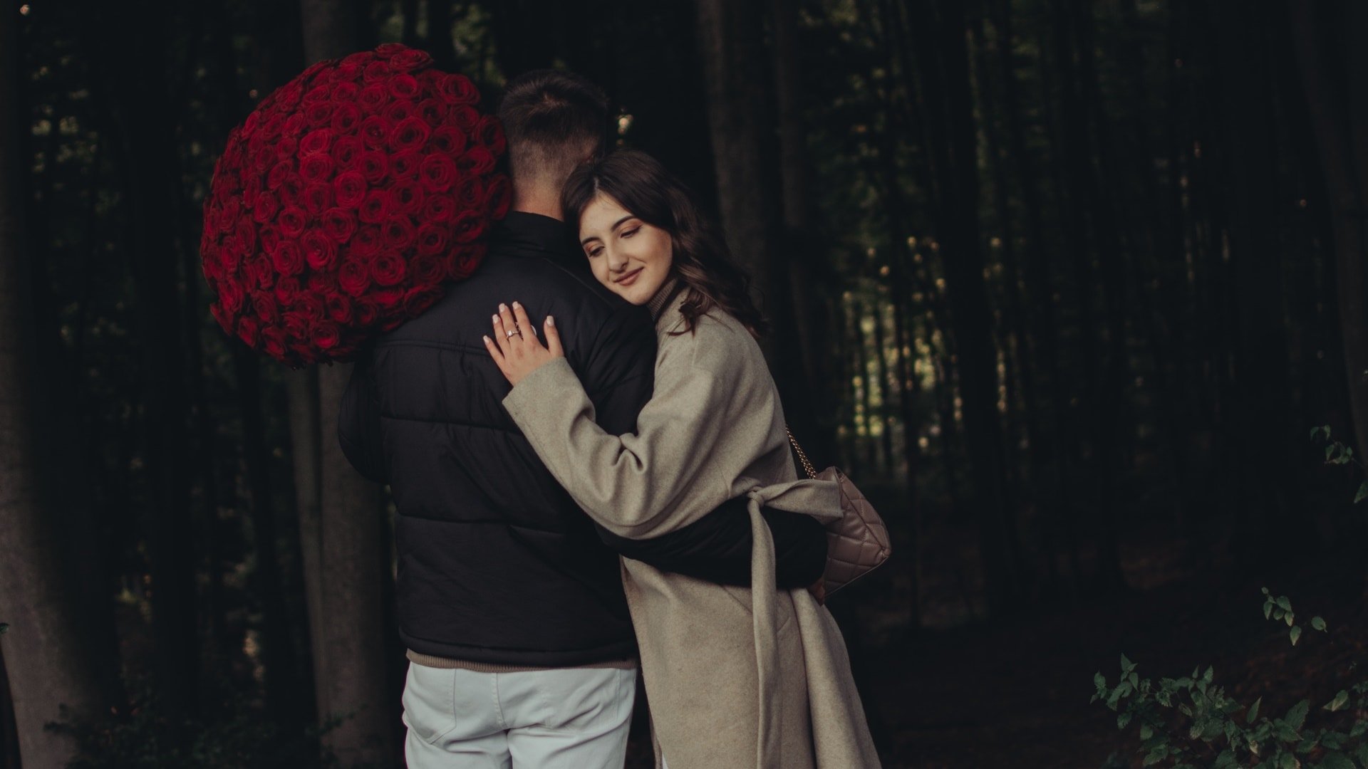 Muž objíma ženu a drží kyticu ruží