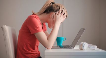 Žena si drží hlavu nad notebookom