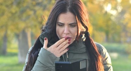 Prekvapená žena pozerá do mobilu