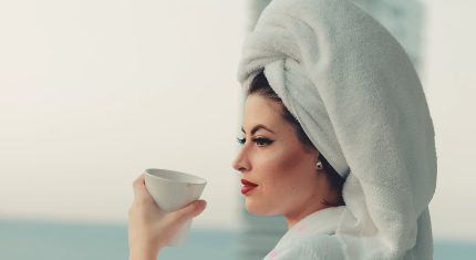 Žena s uterákom na hlave pije ráno kávu