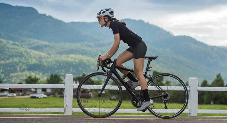 Mladá žena bicykluje v prírode na otvorenej ceste