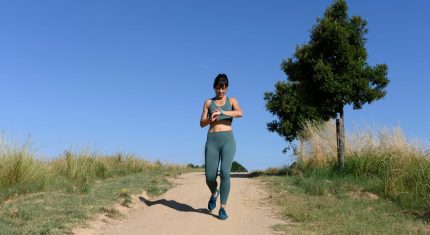 Žena v športovom oblečení kontroluje hodinky v parku