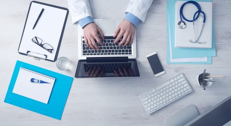 Mladá žena s úsmevom multitaskuje s notebookom a telefónom